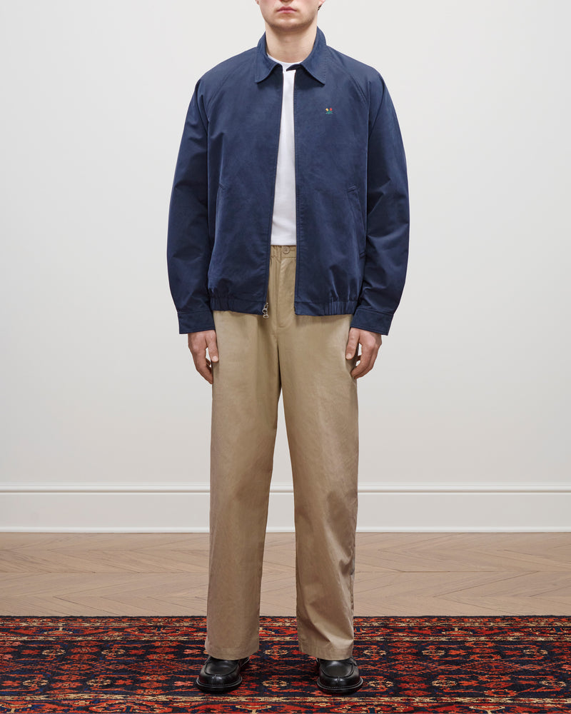 A person in the Crest Casual Jacket, white shirt, beige pants, and black shoes stands on a patterned rug.