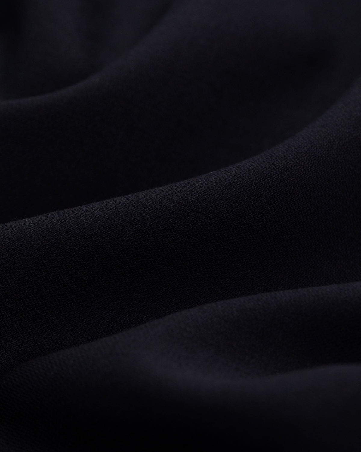 Close-up of Tropical Wool Suit Trouser fabric with soft folds and a smooth, wavy texture.