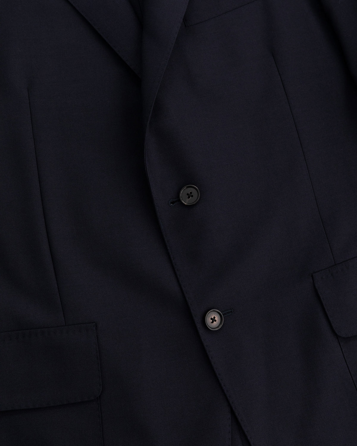 Close-up of the Tropical Wool Suit Jacket in dark navy with two black buttons and front flap pockets.