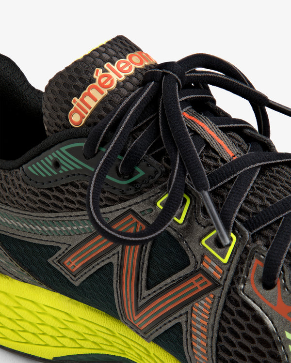 Close-up of the ALD / New Balance 860v2, a black sneaker with colorful accents, black laces, and branded tongue.