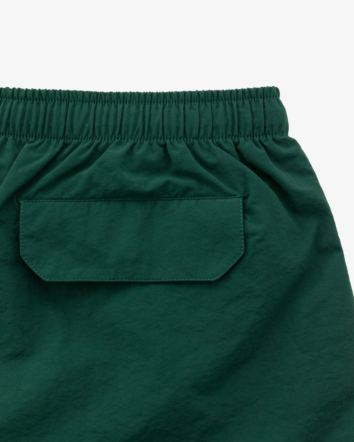 Close-up of Logo Swim Short in dark green with elastic waistband and flap back pocket.