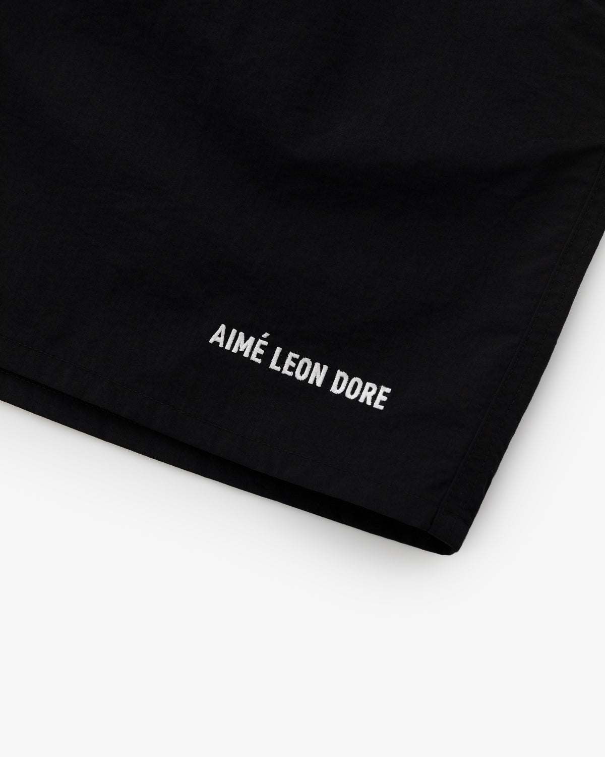 Black Logo Swim Short with AIMÉ LEON DORE embroidered in white near the hem on a white background.