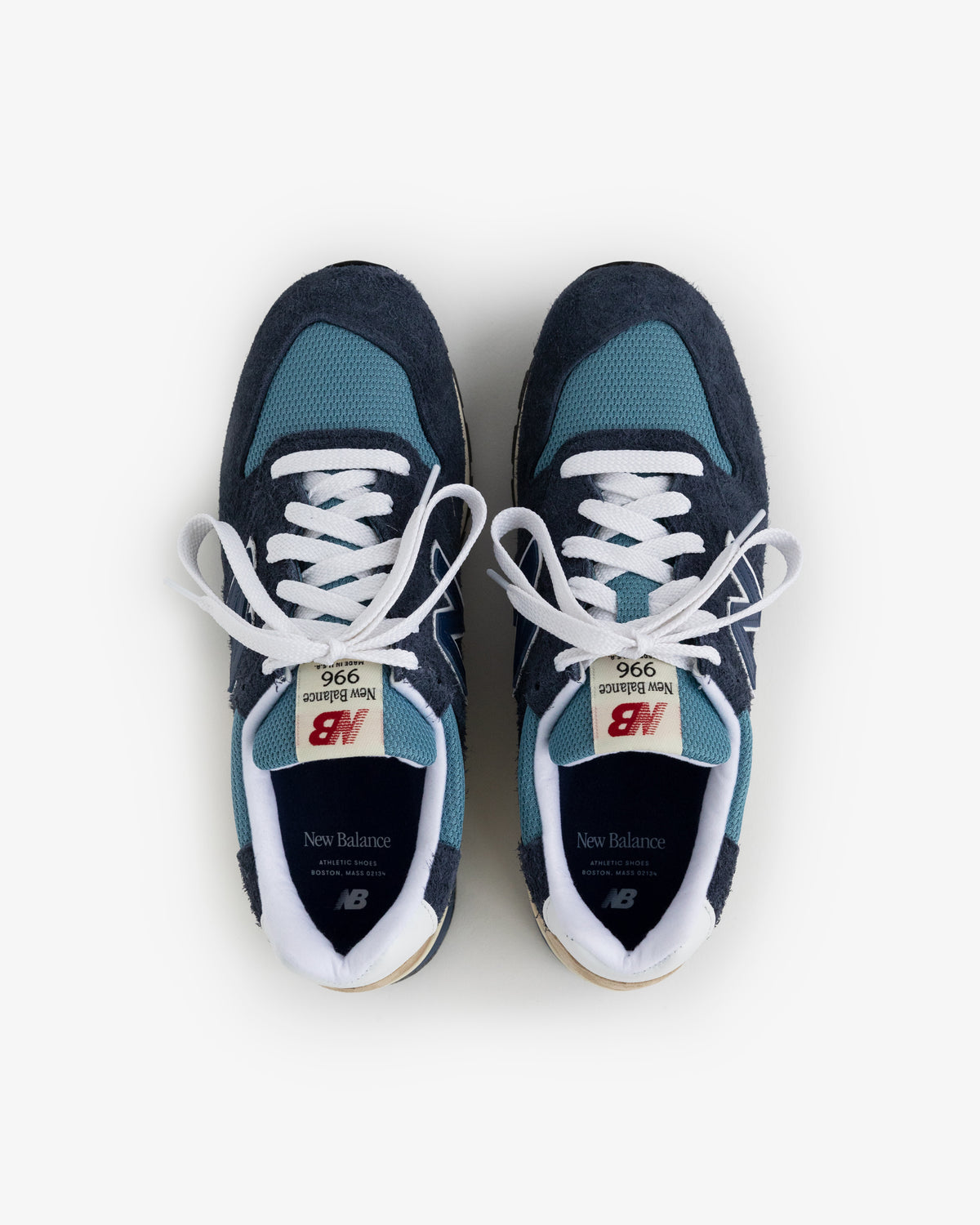 A pair of New Balance Made in USA 996 blue and navy sneakers with white laces, top view on a white background.