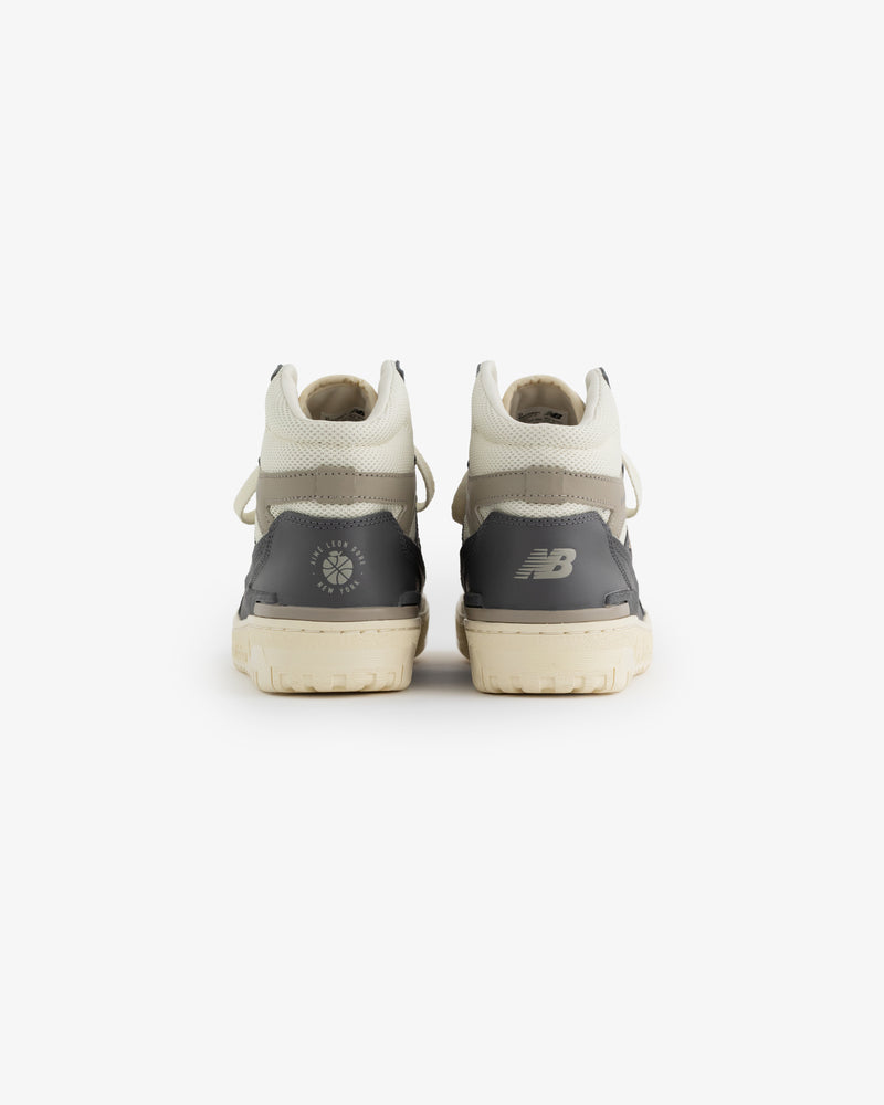 A pair of gray and white ALD / New Balance 650R sneakers shown from the back, displaying heel logos.