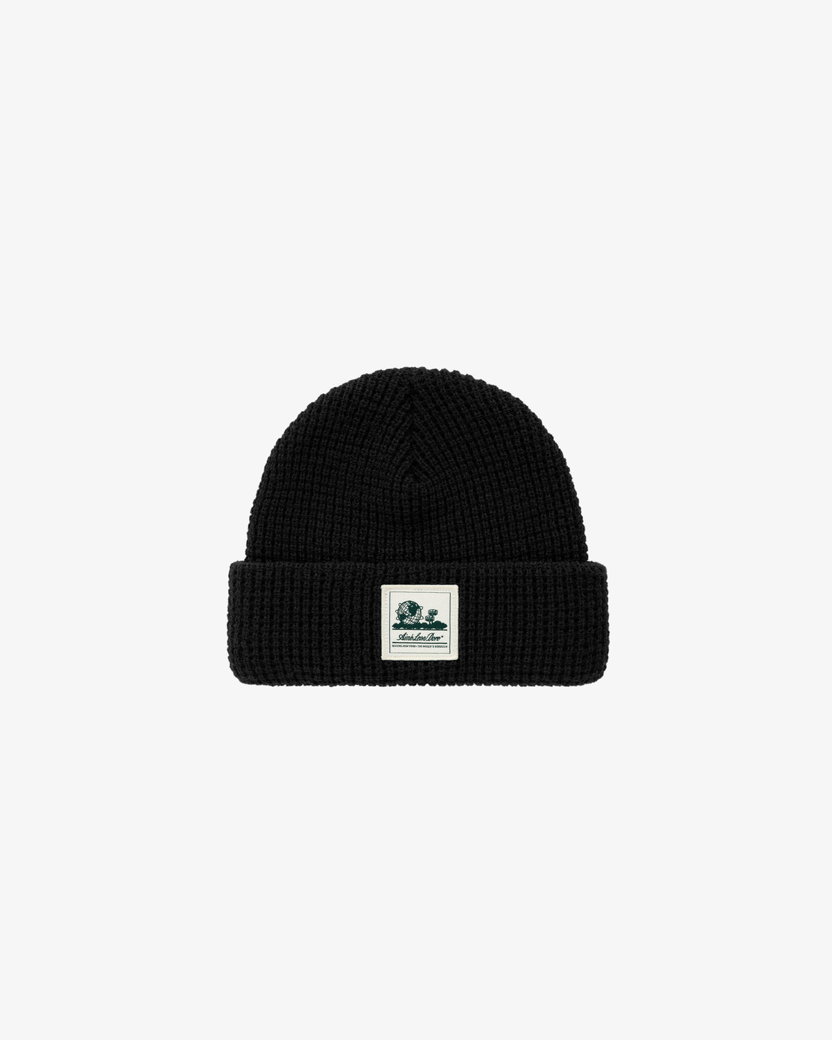 The Waffle Knit Beanie in black features a folded brim and a white front patch, shown on a plain background.